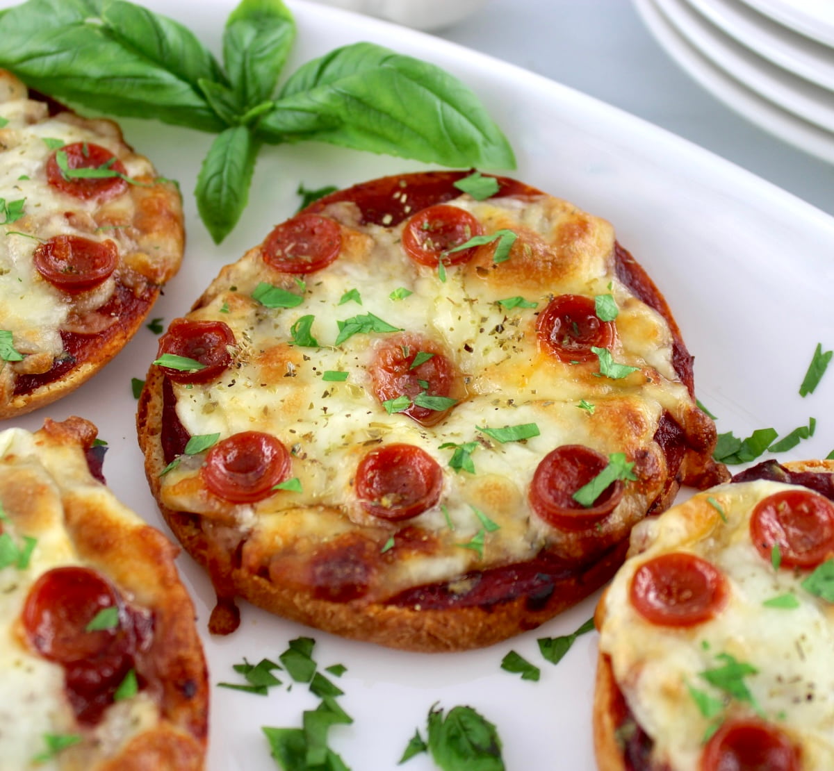 closeup of Pepperoni Pizza Bagels on white plate with fresh basil