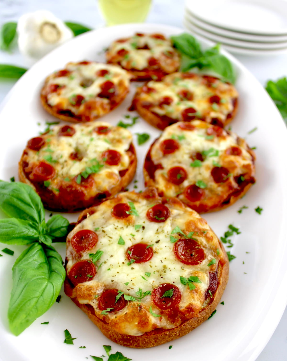closeup of Pepperoni Pizza Bagels on white plate with fresh basil