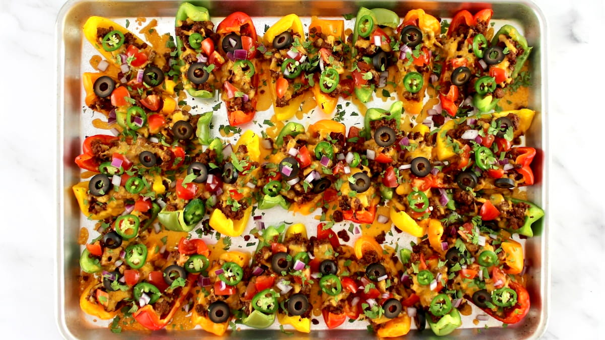 Baking sheet loaded with bell peppers with melted cheese and nacho toppings