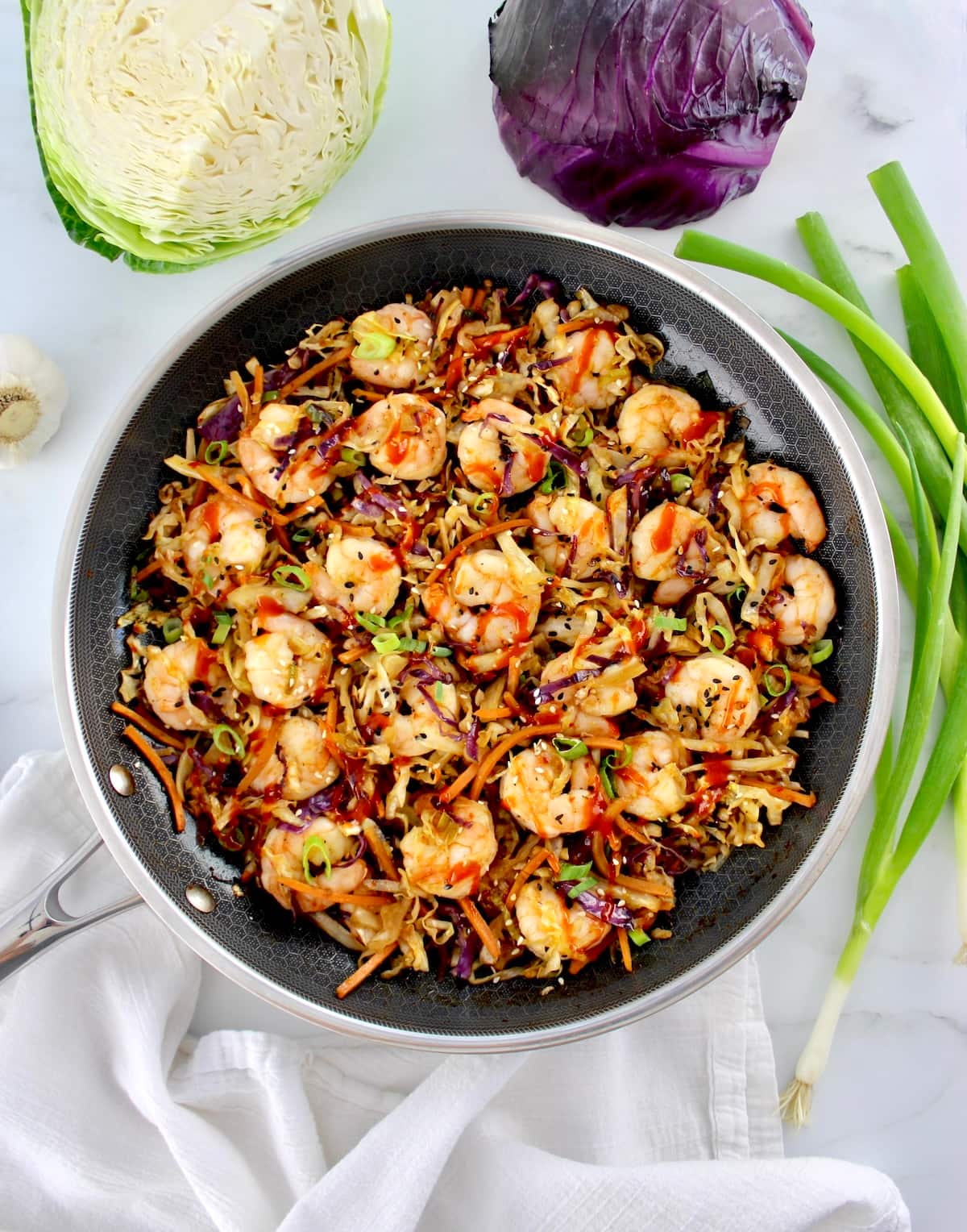 overhead view of Shrimp Egg Roll in a Bowl in skillet with red and green cabbage in back