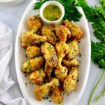 Air Fryer Garlic Parmesan Wings on white oval platter with butter sauce and parsley on side