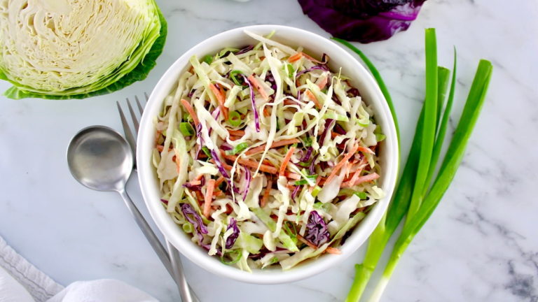 coleslaw in a white bowl with a green onion garnish