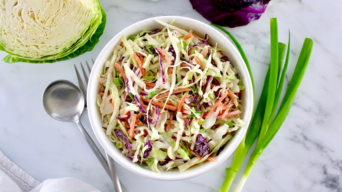 coleslaw in a white bowl with a green onion garnish