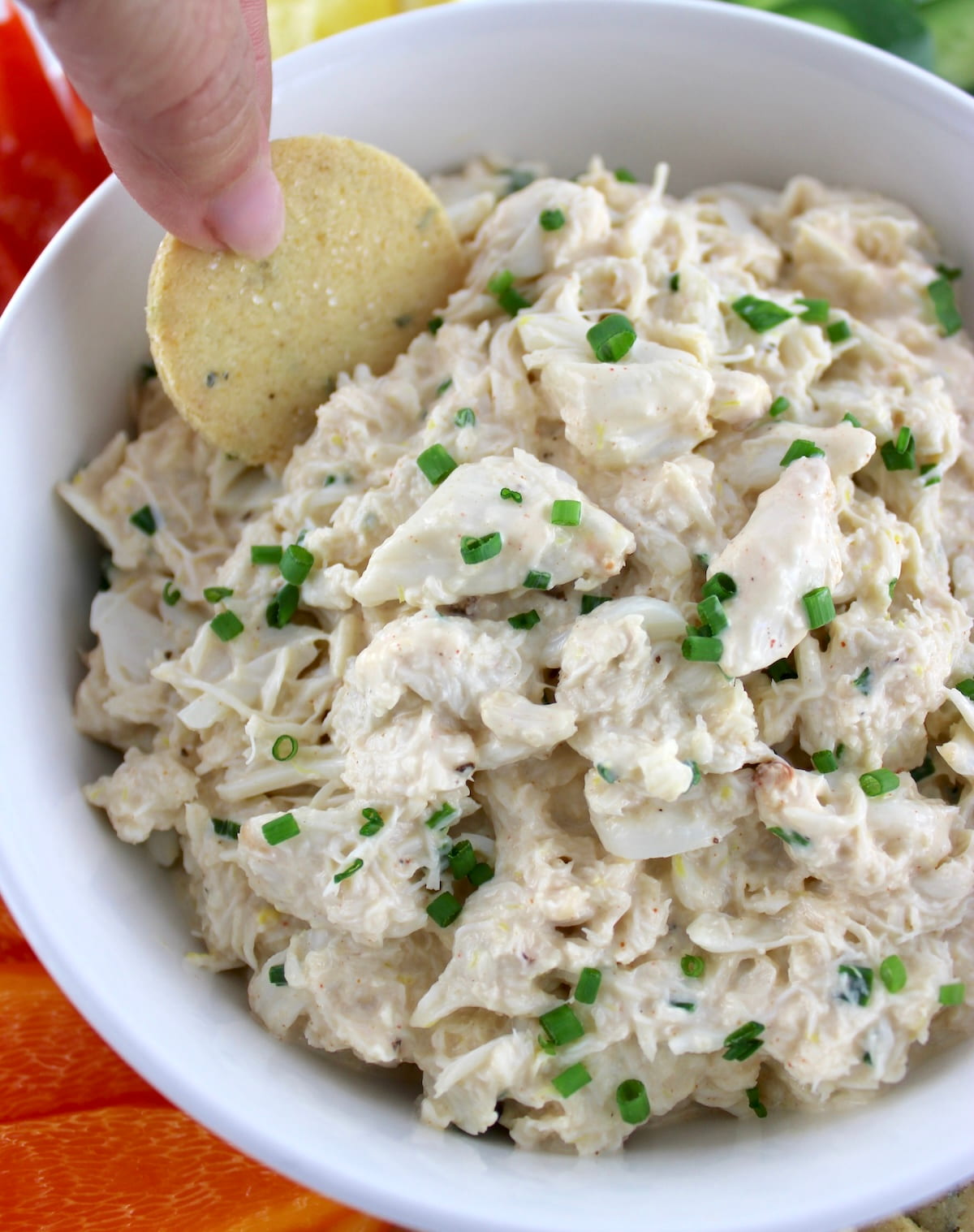 Cold Crab Dip in white bowl with keto cracker being dipped in