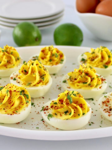 Side horizontal view of Deviled Eggs with Tajín on white platter