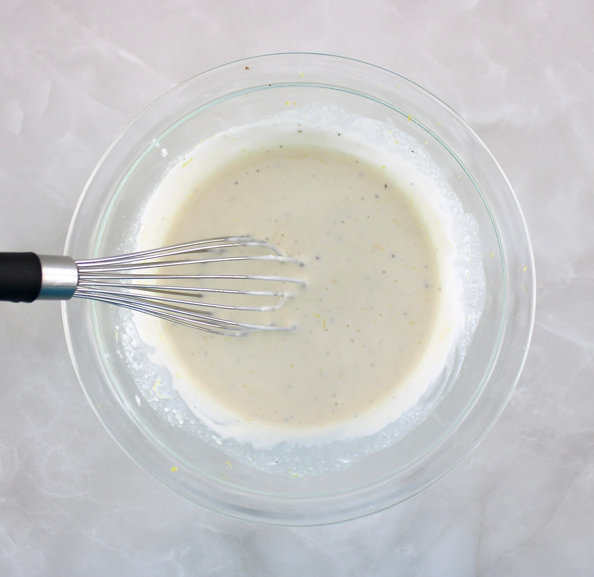 Dill Pickle Chicken Salad dressing in glass bowl with whisk