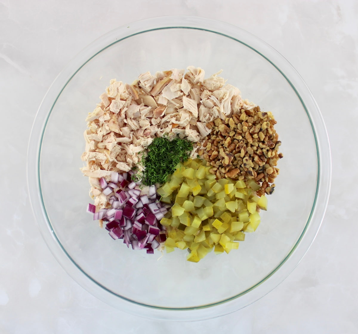 Dill Pickle Chicken Salad ingredients in glass bowl unmixed in sections
