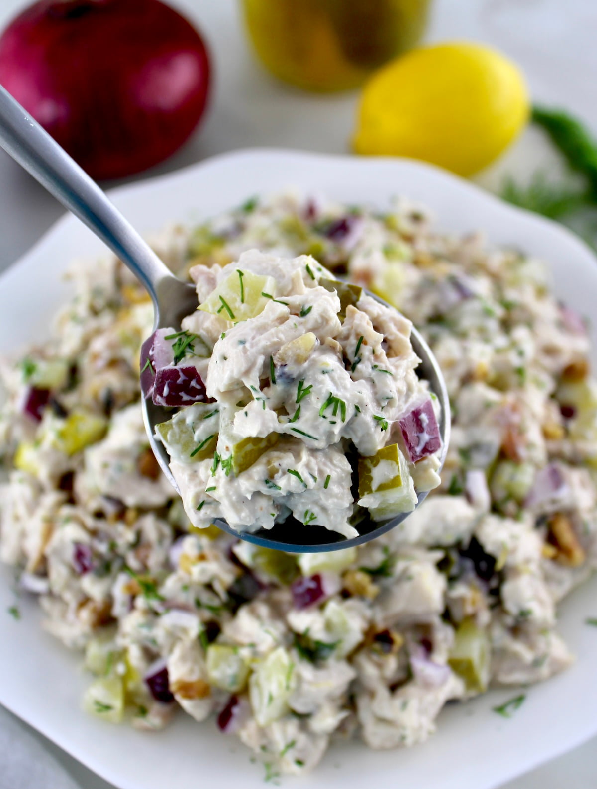 closeup of Dill Pickle Chicken Salad in spoon held up over white bowl