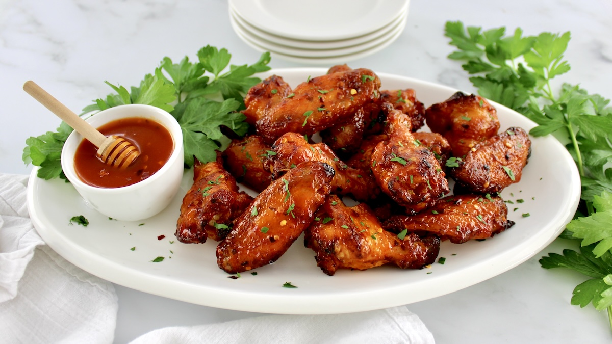Hot Honey Chicken Wings on white oval plate with hot honey sauce on side