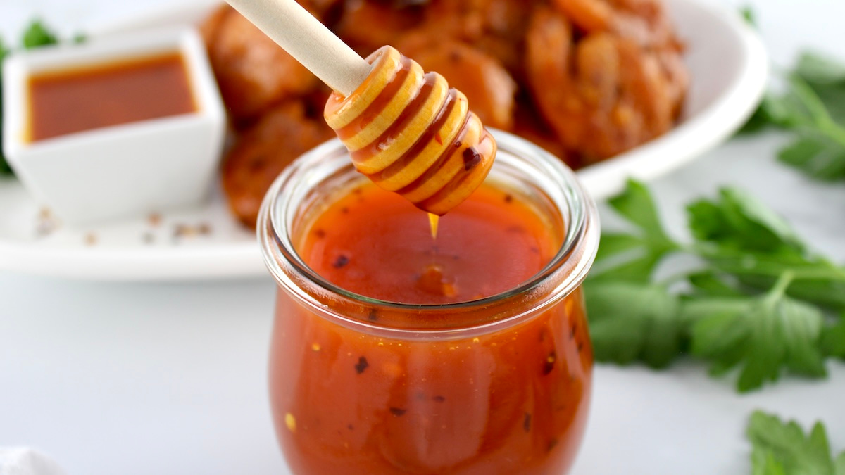 small glass jar or hot honey sauce with a wooden honey dipper