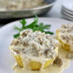 closeup of Keto Biscuits and Gravy on white plate with skillet in back