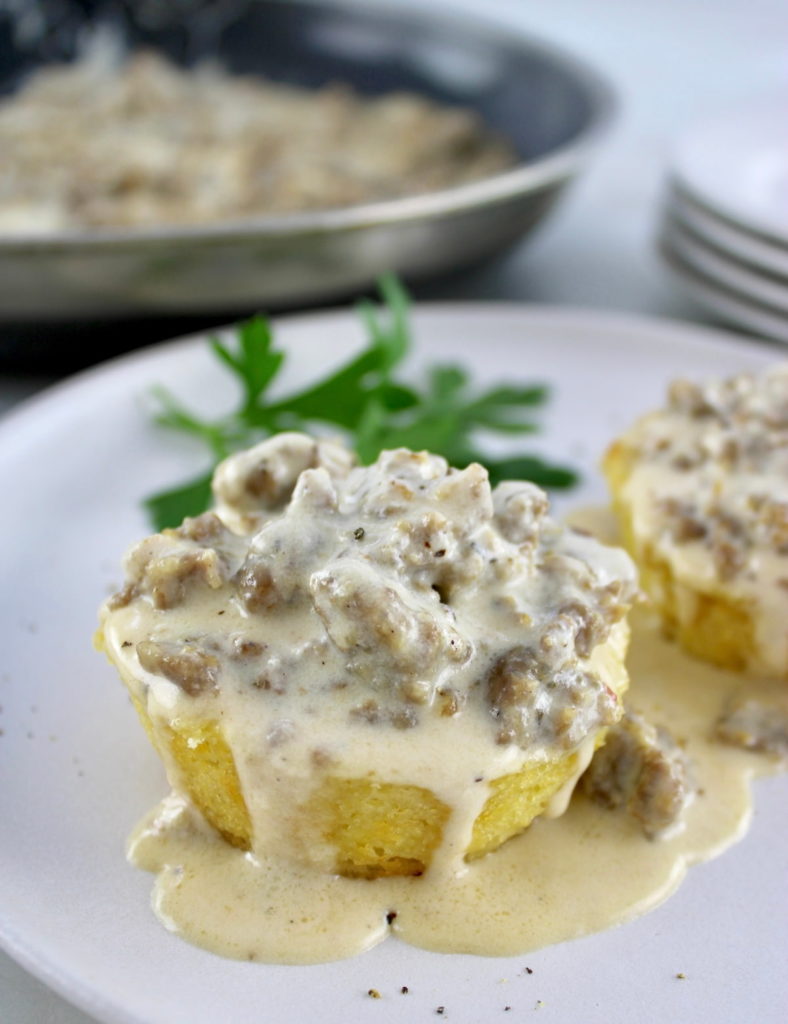 closeup of Keto Biscuits and Gravy on white plate with skillet in back
