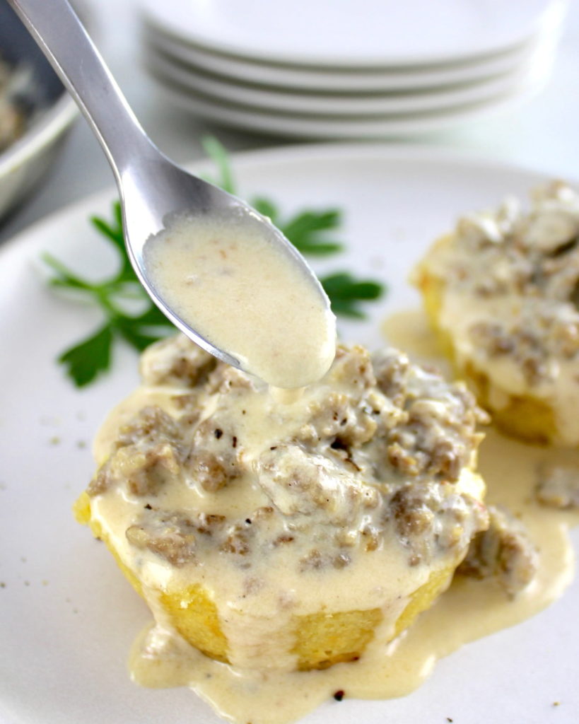 closeup of Keto biscuit with sausage gravy being spooned over top