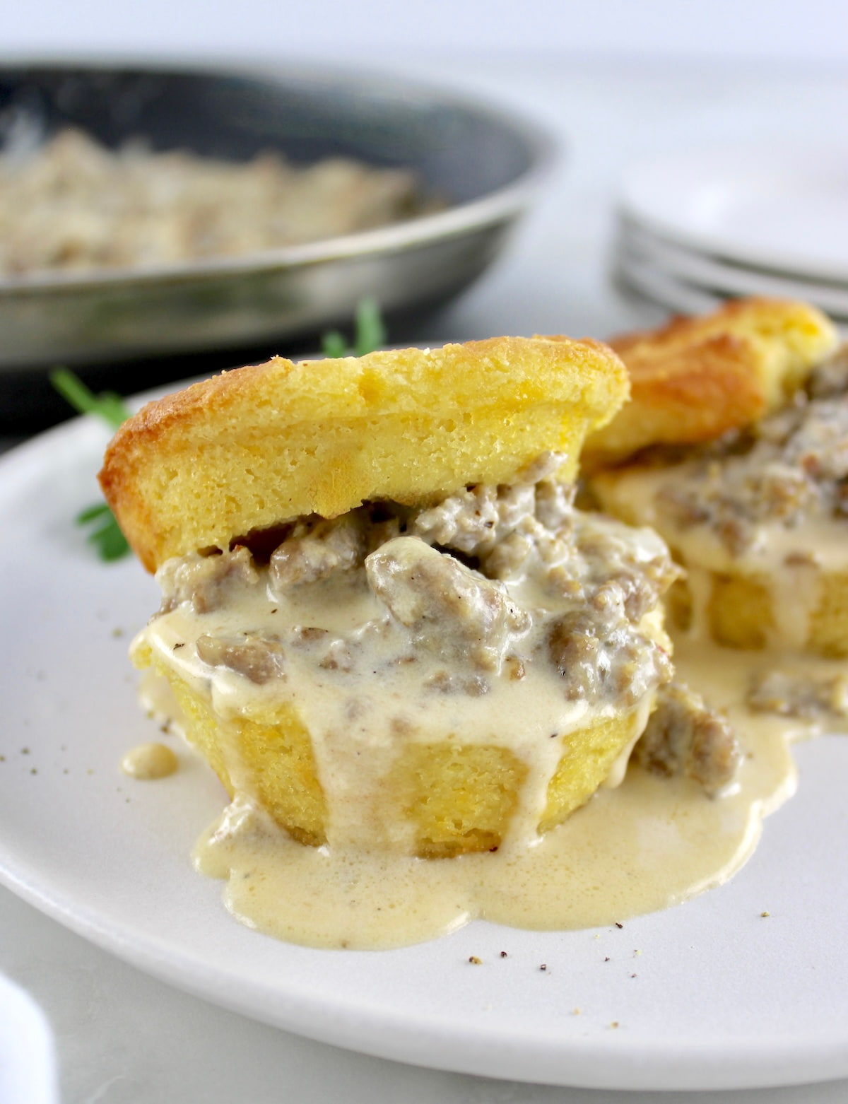 Keto Biscuits and Gravy on white plate with skillet in back