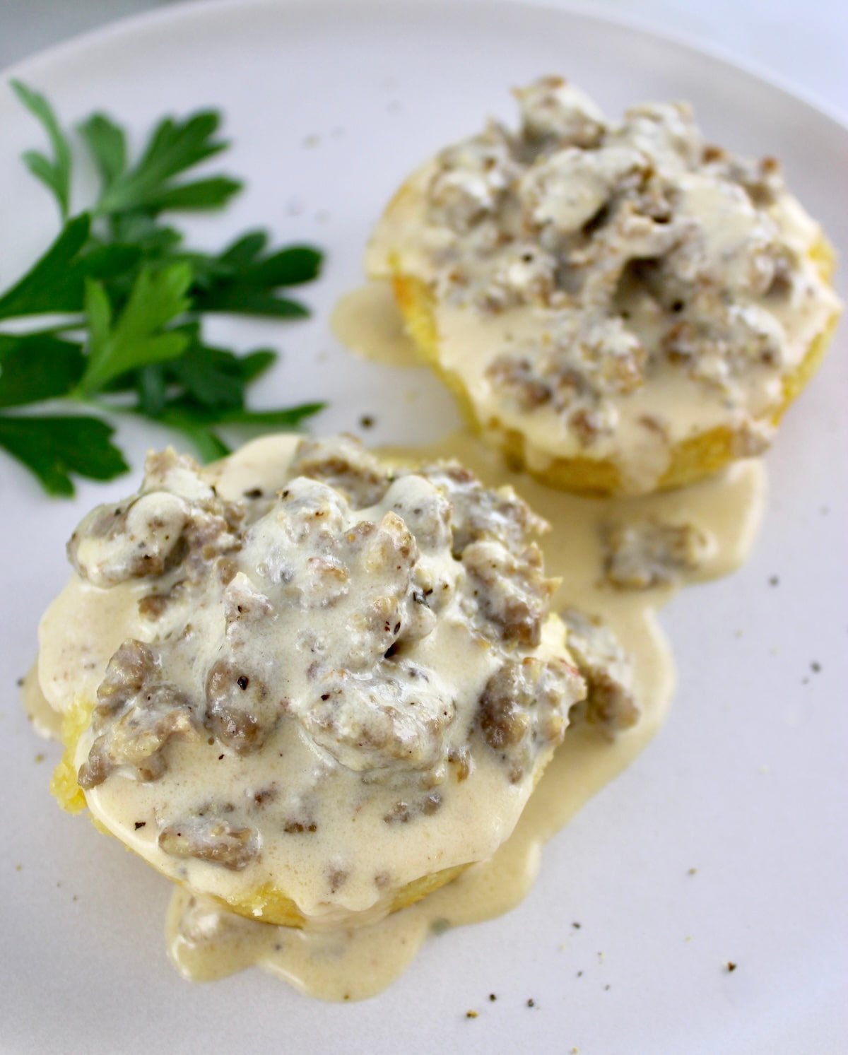 overhead view of Keto Biscuits and Gravy on white plate with parsley garnish