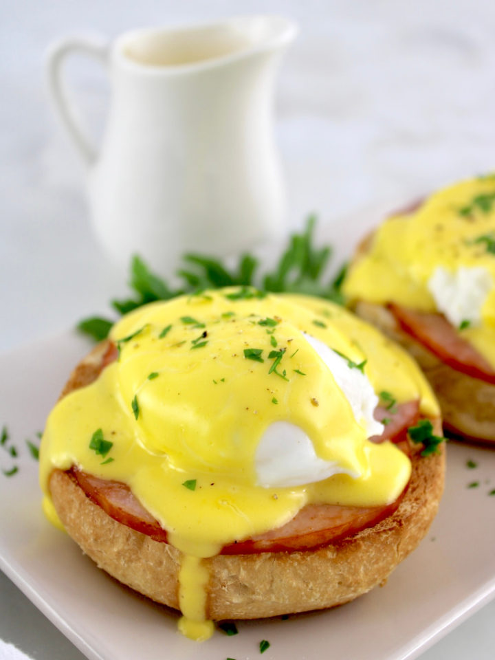 closeup of Keto Eggs Benedict on plate with hollandaise dripping off the side and more sauce in back