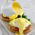 hollandaise sauce being poured over Keto Eggs Benedict