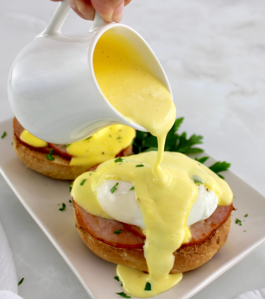 hollandaise sauce being poured over Keto Eggs Benedict