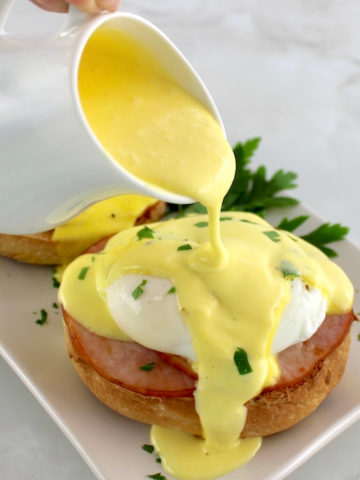 hollandaise sauce being poured over Keto Eggs Benedict