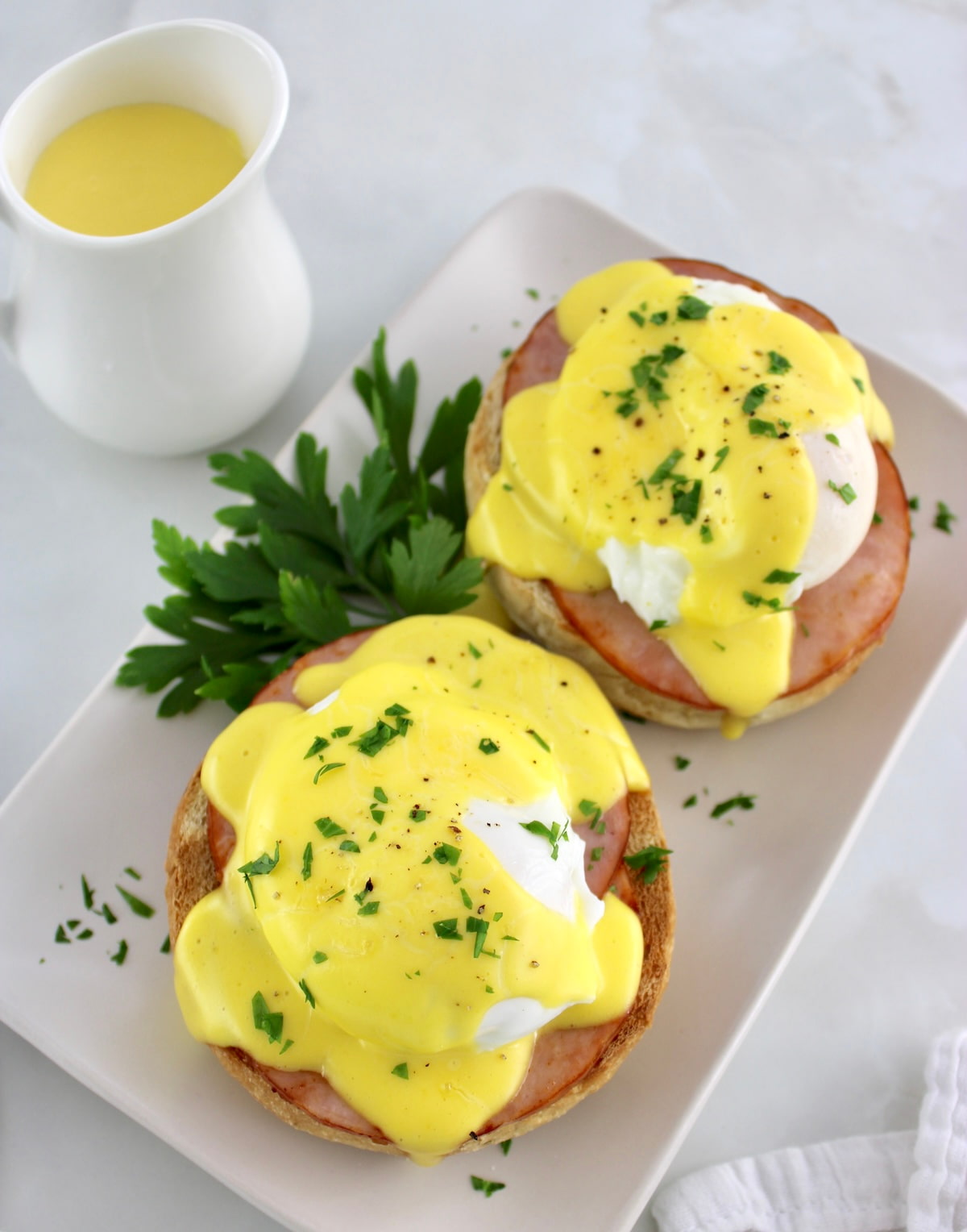overhead view of Keto Eggs Benedict on plate with hollandaise dripping off the side and more sauce in back