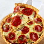 holding up slice of Keto Sausage and Pepperoni Pizza Pie