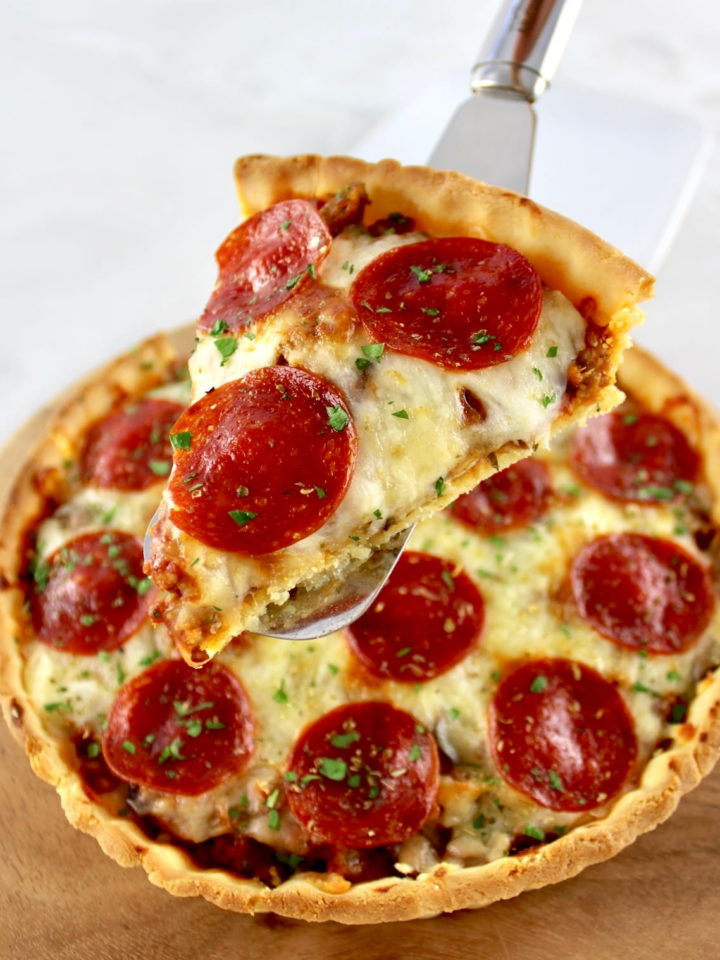 holding up slice of Keto Sausage and Pepperoni Pizza Pie
