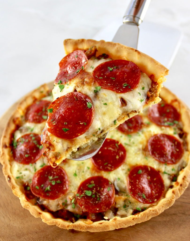 holding up slice of Keto Sausage and Pepperoni Pizza Pie