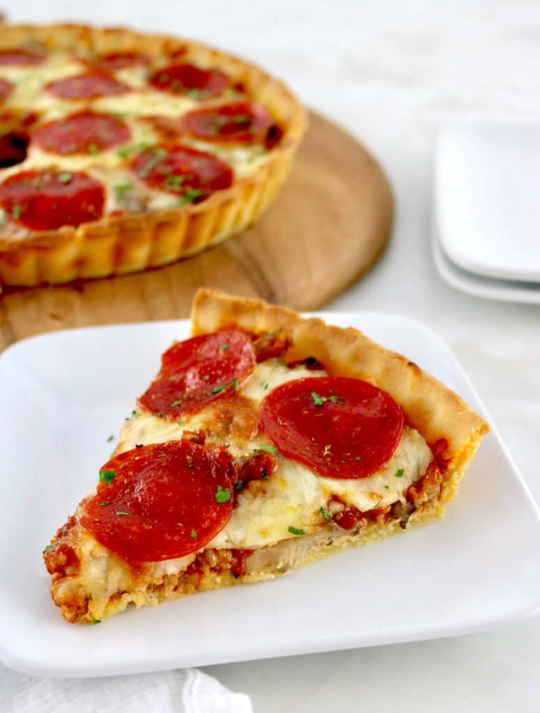 slice of Keto Sausage and Pepperoni Pizza Pie on white plate with pie on back