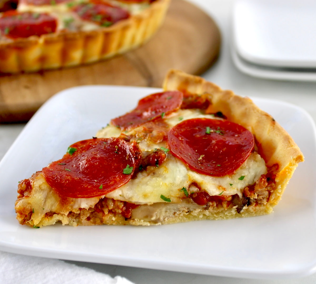 closeup of slice of Keto Sausage and Pepperoni Pizza Pie on white plate