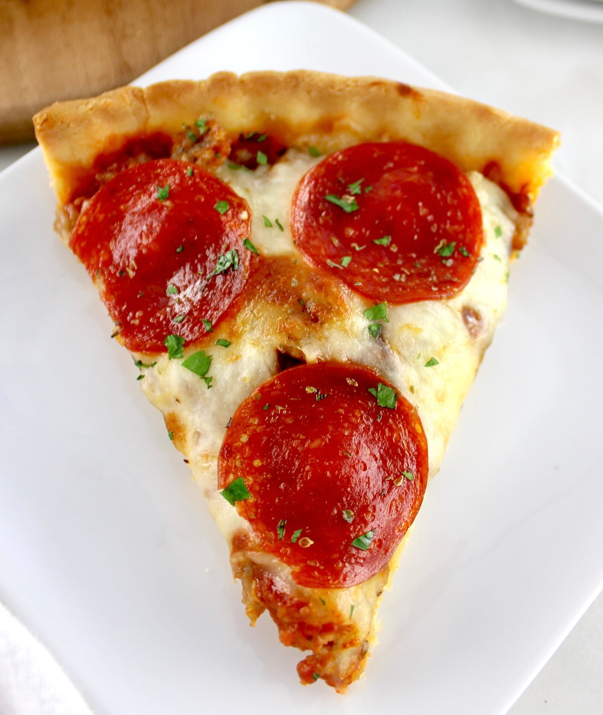 overhead view of slice of Keto Sausage and Pepperoni Pizza Pie on white plate