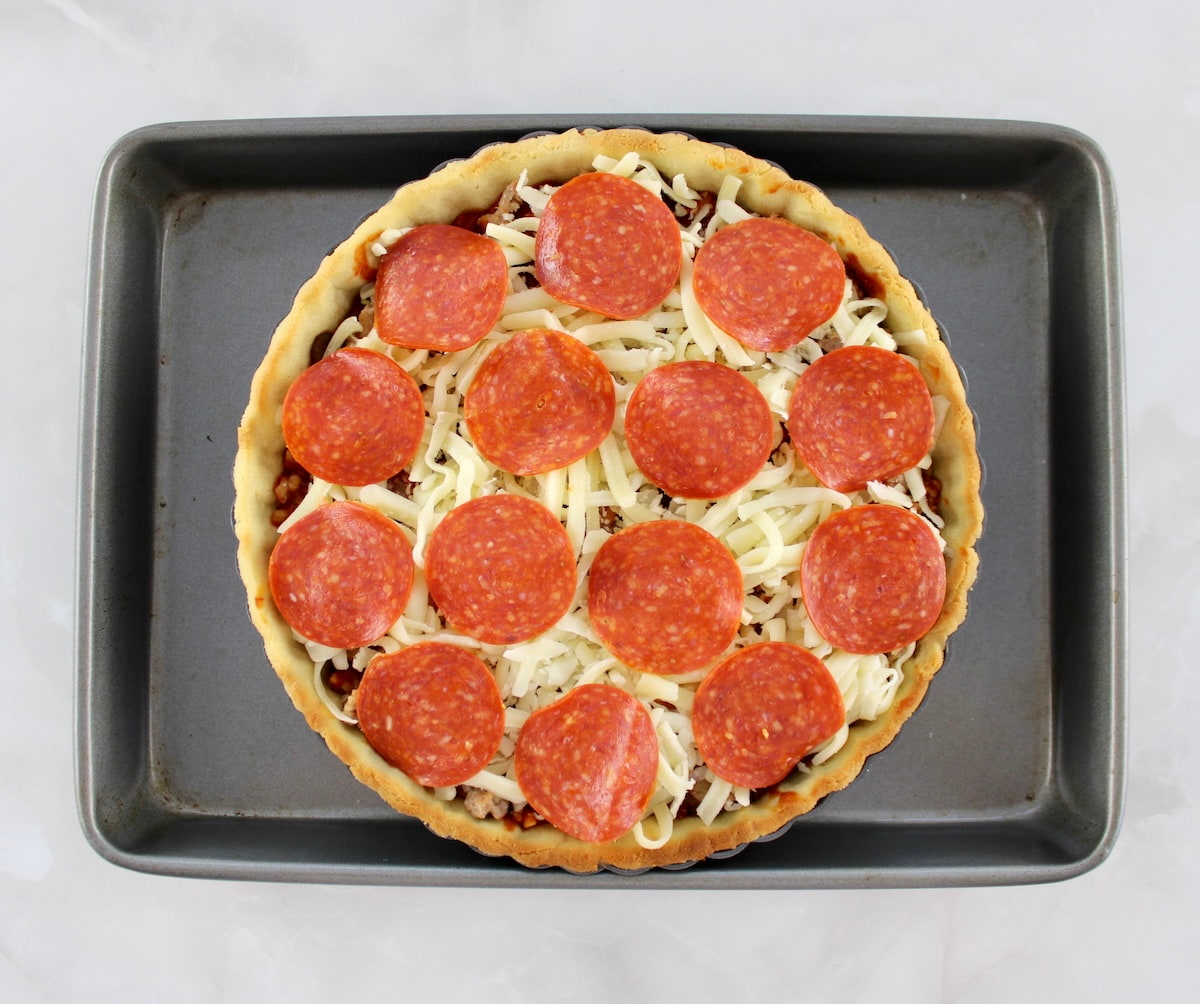 Keto Sausage and Pepperoni Pizza Pie unbaked on baking sheet