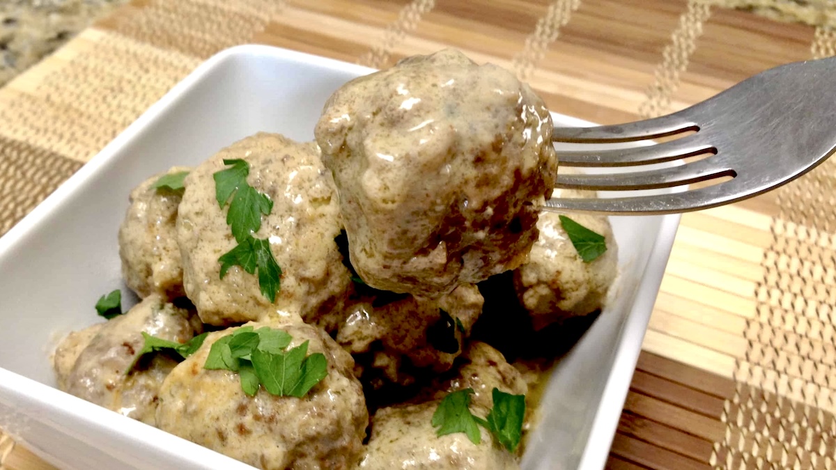 Keto Swedish Meatball held up by fork over white bowl