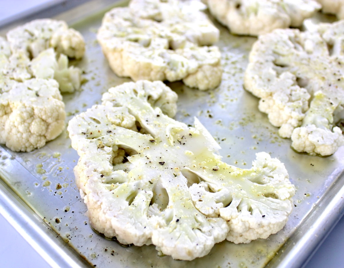closeup of cauliflower steak brushed with olive oil, salt and pepper on baking sheet