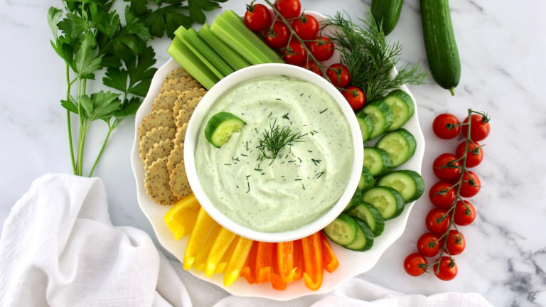 whipped cottage cheese dip on a white plate with sliced veggies