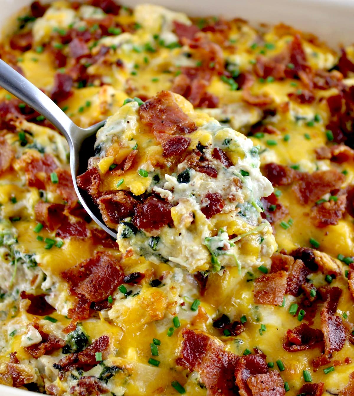 scooping out piece of Bacon Ranch Chicken Casserole with silver serving spoon