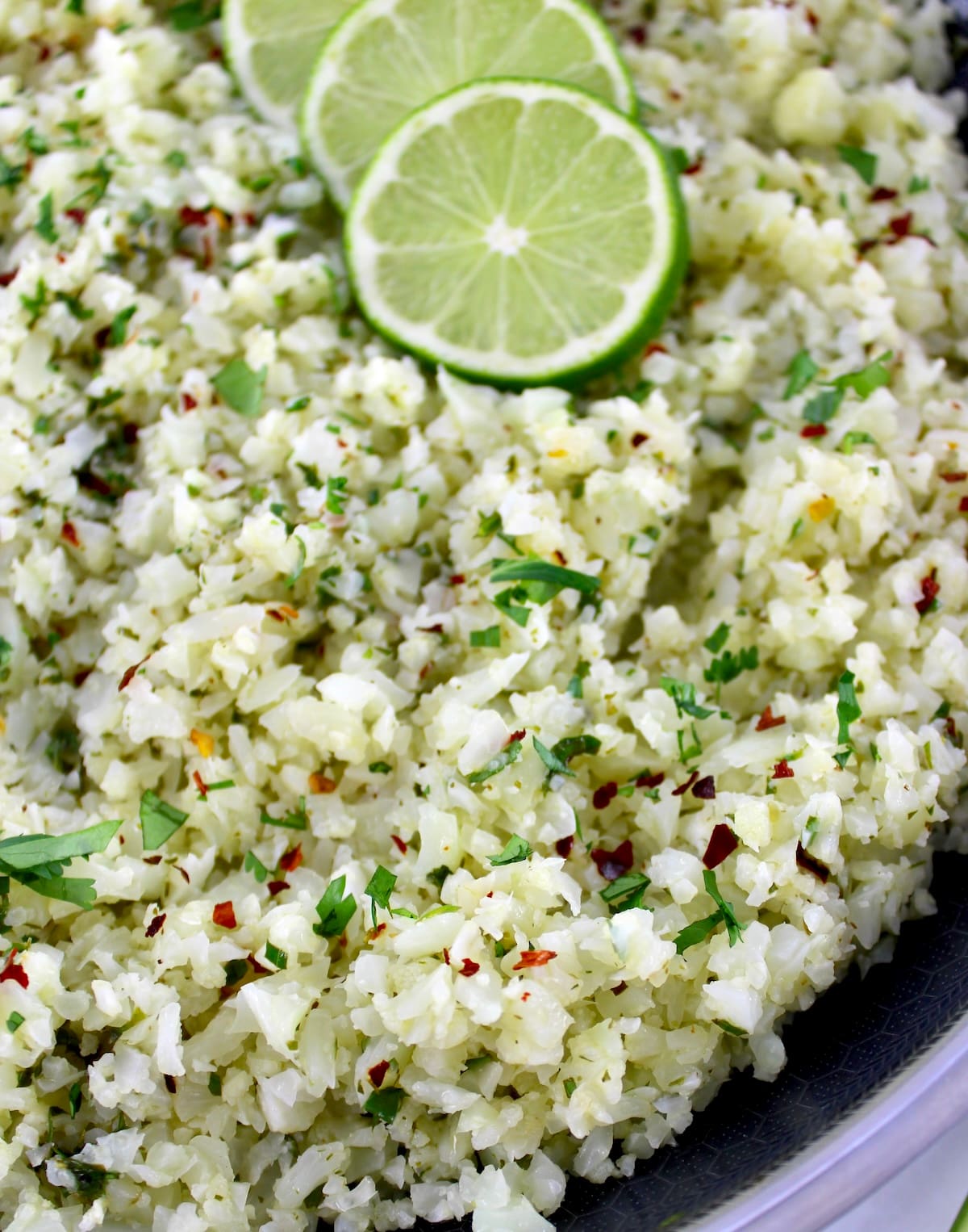 closeup of Chimichurri Cauliflower Rice in skillet with lime slices