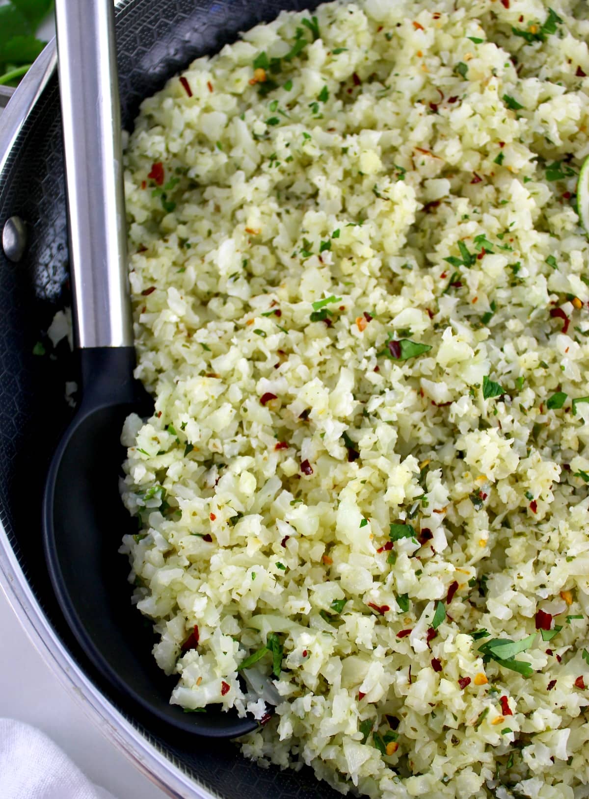 closeup of Chimichurri Cauliflower Rice with black serving spoon on side