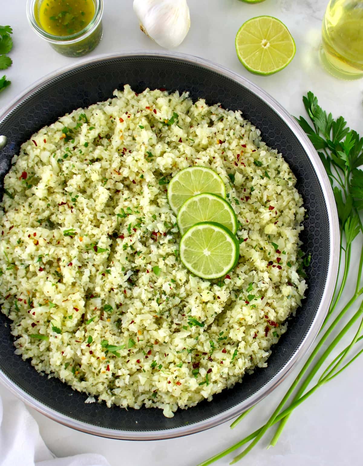 overhead view of Chimichurri Cauliflower Rice in skillet with lime slices