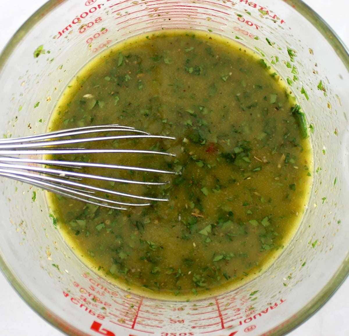 chimichurri sauce in mixing bowl with whisk