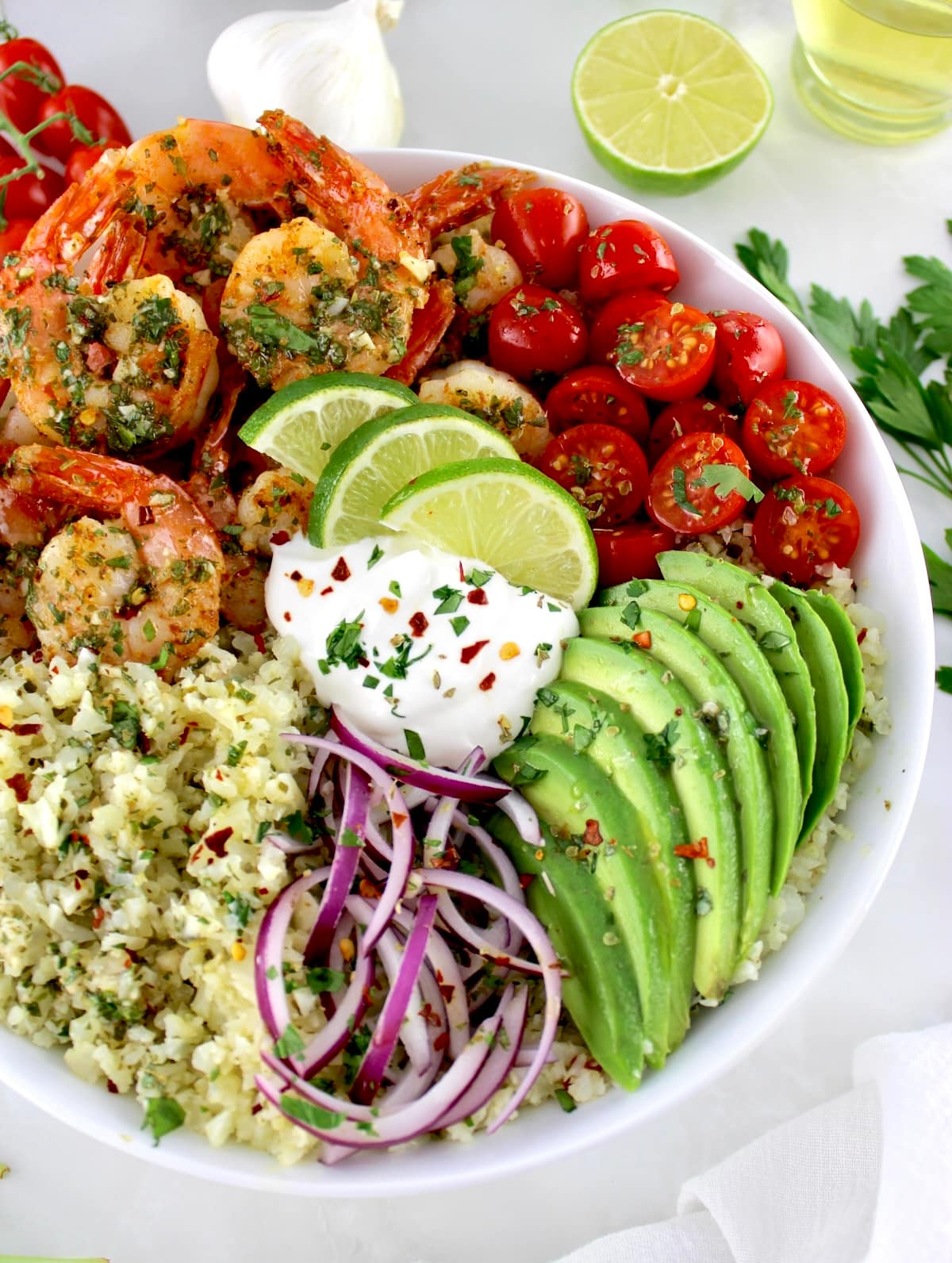 closeup of Chimichurri Shrimp Avocado Bowl in white bowl with chopped cilantro and sour cream