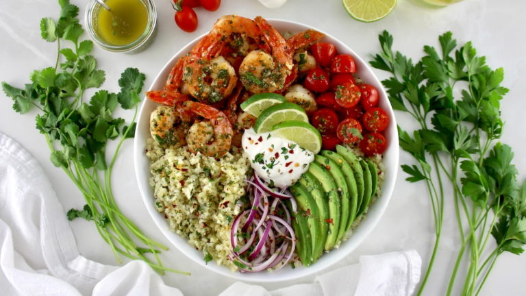 overhead view of Chimichurri Shrimp Avocado Bowl in white bowl with chopped cilantro and sour cream on top