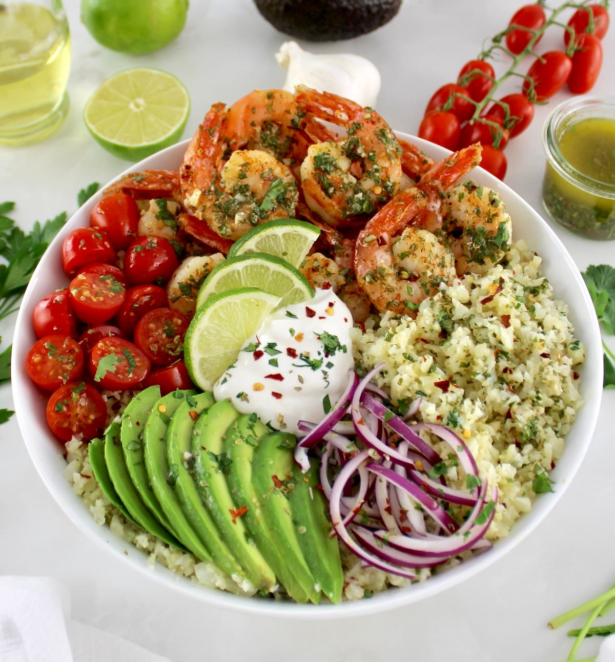 closeup of Chimichurri Shrimp Avocado Bowl in white bowl with chopped cilantro and sour cream on top