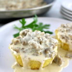 closeup of Keto Biscuits and Gravy on white plate with skillet in back