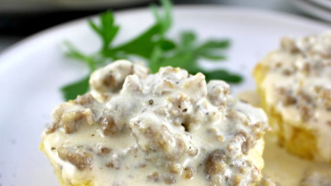 closeup of Keto Biscuits and Gravy on white plate with skillet in back