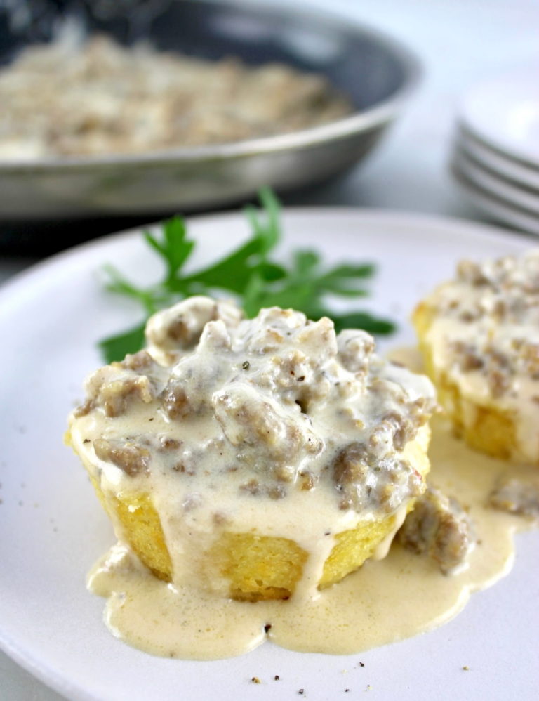 closeup of Keto Biscuits and Gravy on white plate with skillet in back