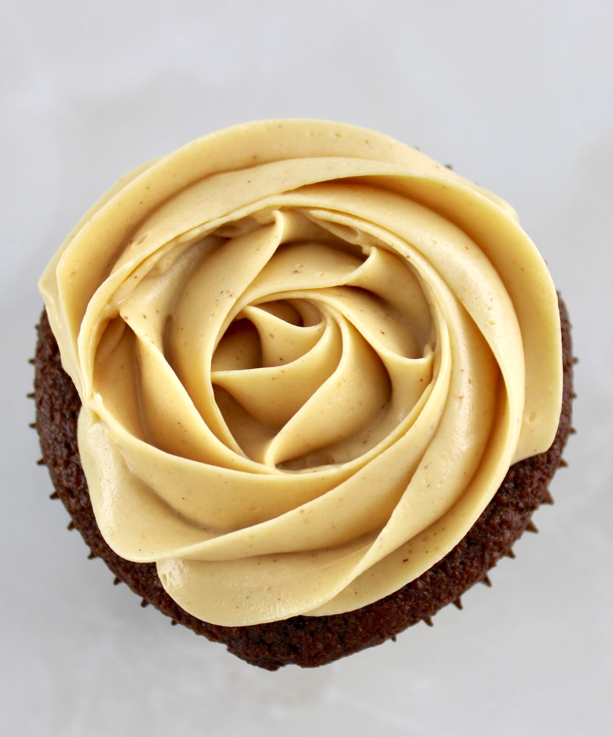 overhead view of Keto Peanut Butter Frosting piped in a rosette on chocolate cupcake