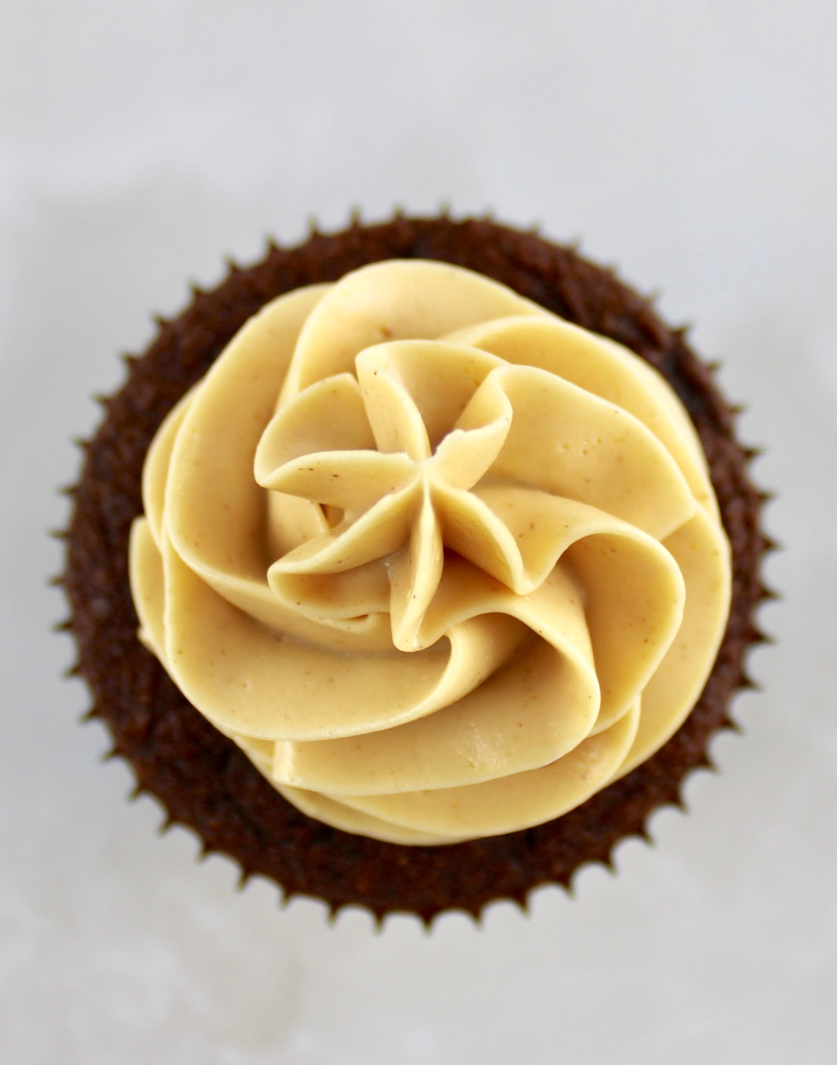 overhead view of Keto Peanut Butter Frosting piped onto chocolate cupcake