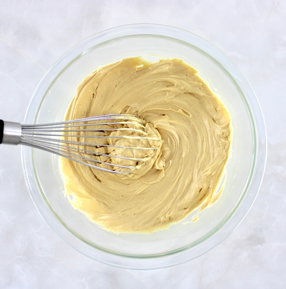 Keto Peanut Butter Frosting in glass bowl with whisk