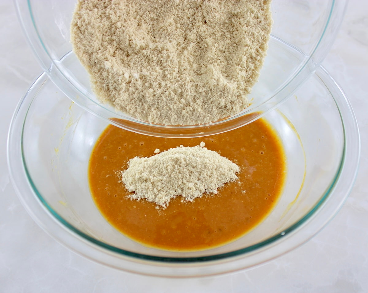 Keto Pumpkin Coffee Cake Muffins dry ingredients pouring into the wet in glass bowls