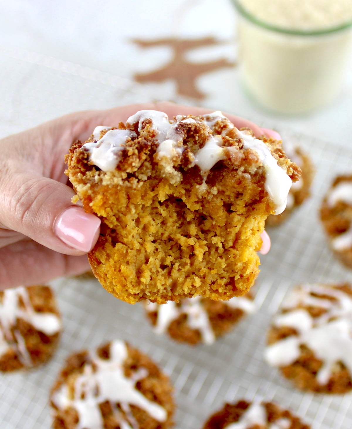 holding up Keto Pumpkin Coffee Cake Muffin with bite missing